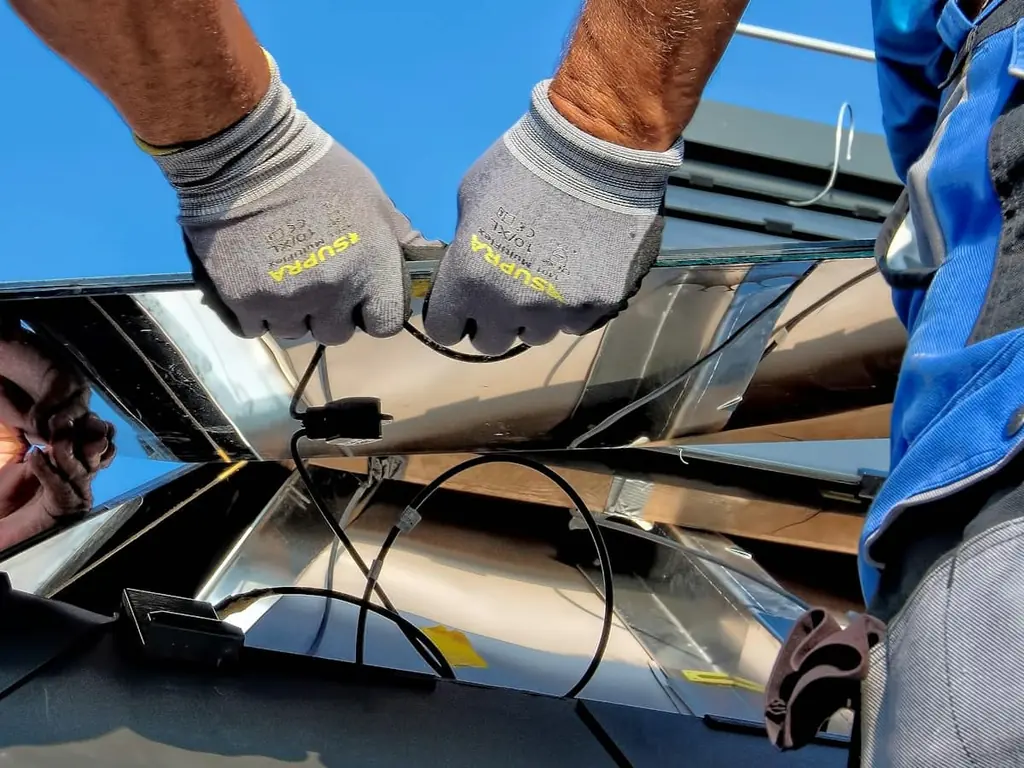 Installer connecting the wiring under a solar panel